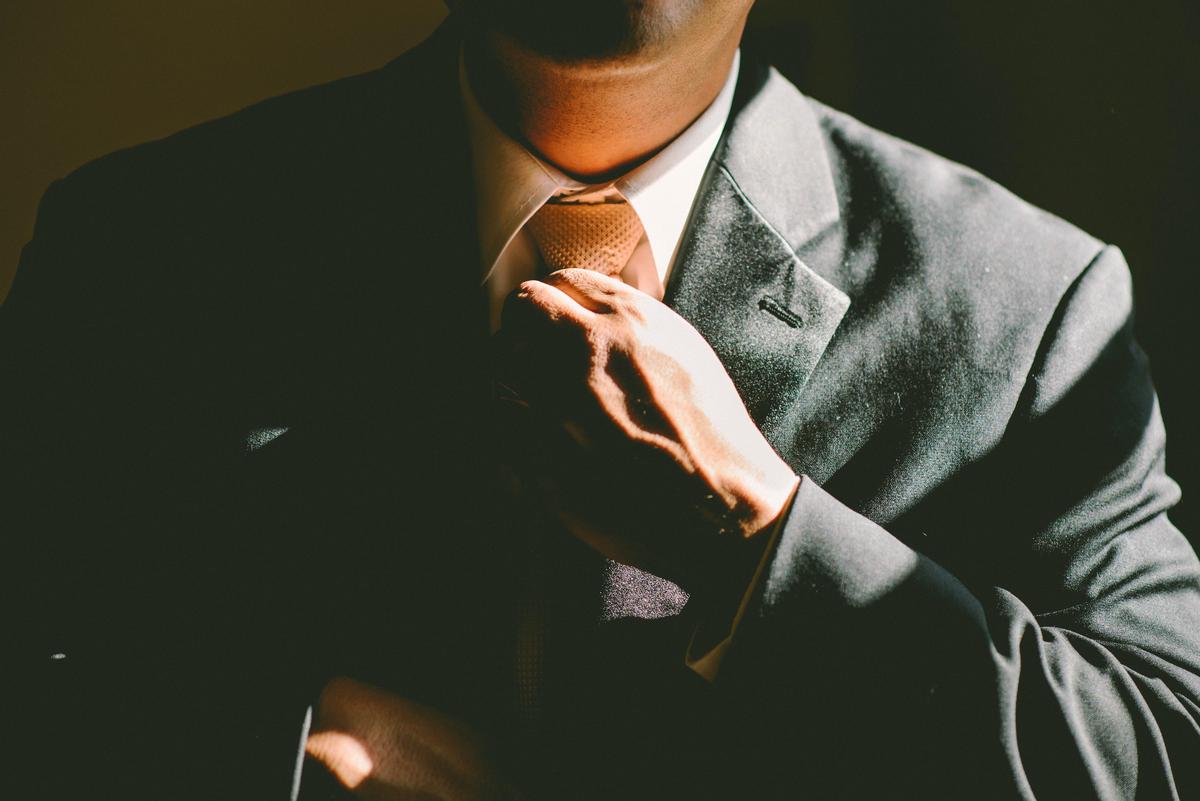 A person in a business suit standing confidently with their arms crossed, representing a strong professional presence.